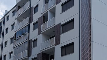 Un immeuble résidentiel à plusieurs étages, doté de balcons, de fenêtres et d’une façade en briques.