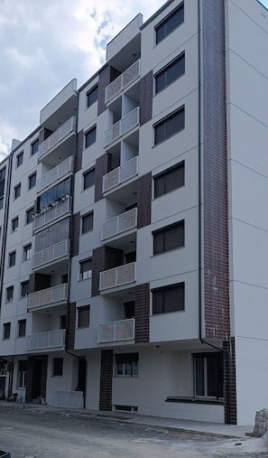 Un edificio residencial de varios pisos con balcones, ventanas y fachada de ladrillo.