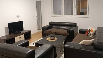 Ein Wohnzimmer mit einer Couch, einem Couchtisch und einem Fernseher.