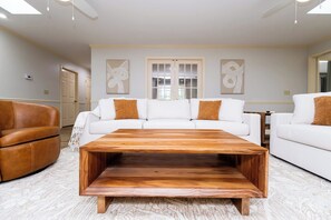 Ein Wohnzimmer mit einem weißen Sofa, einem braunen Ledersessel und einem Holztisch.