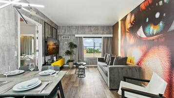 A modern living space with a dining area, a sofa, and a large abstract painting on the wall.