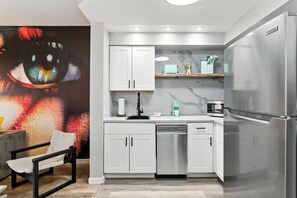 A modern kitchen with white cabinetry, a built-in dishwasher, a refrigerator, and a marble backsplash. - 1BR ADA Apartment 5 min to Epic Universe (Orlando)