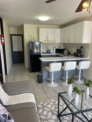 A modern kitchen with a refrigerator, stove, and bar stools. - Cozy 2BR in Carolina 12min to Beach & Airport Near All (Carolina)