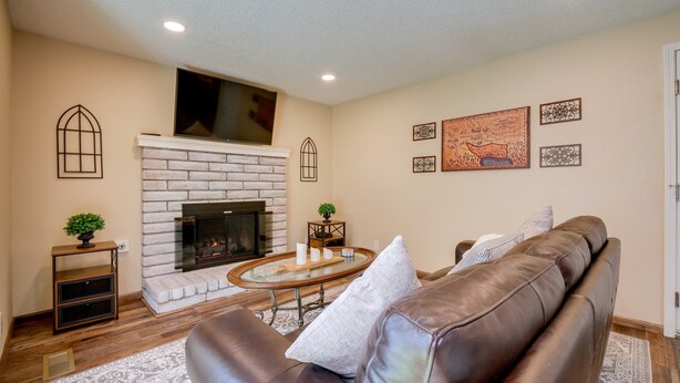 A living room with a fireplace, leather sofa, and decorative wall art. - Modern 4BR Sparks Retreat Hot Tub near Reno/Tahoe (Sparks)