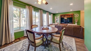 A dining area with a round table and chairs, a ceiling fan, and a large window with curtains. - Modern 4BR Sparks Retreat Hot Tub near Reno/Tahoe (Sparks)