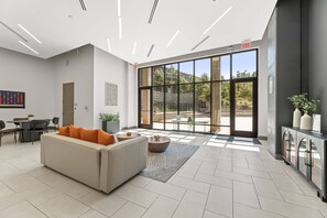 Eine moderne Lobby mit einer Couch, einem Essbereich und großen Fenstern.
