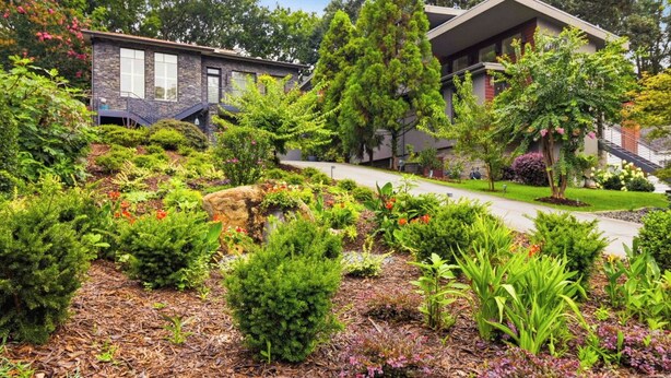 Ein Wohnhaus mit angelegtem Garten, einem gepflasterten Weg und einem modernen, zweistöckigen Haus mit Satteldach.