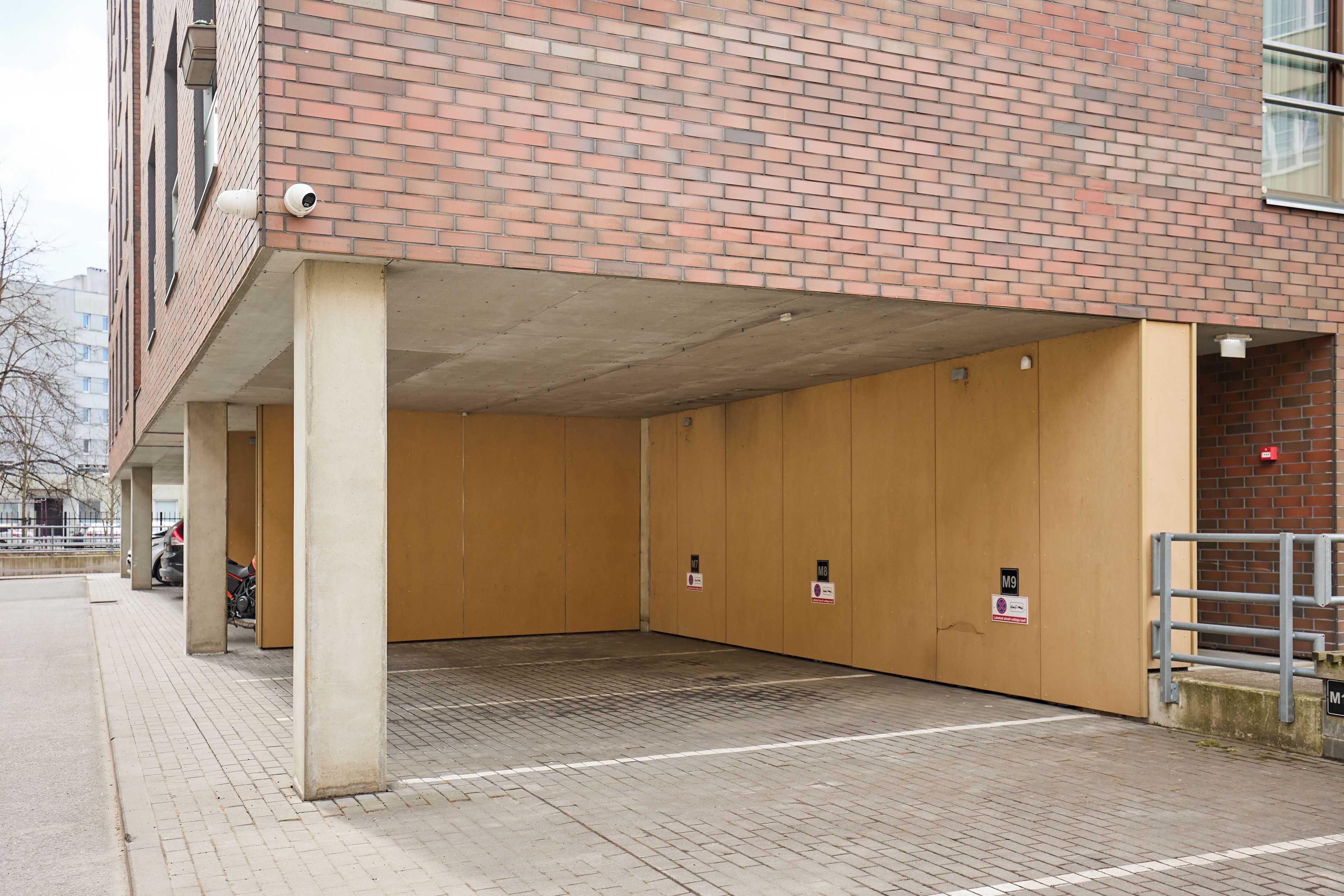 A parking garage with concrete pillars and a brick wall.