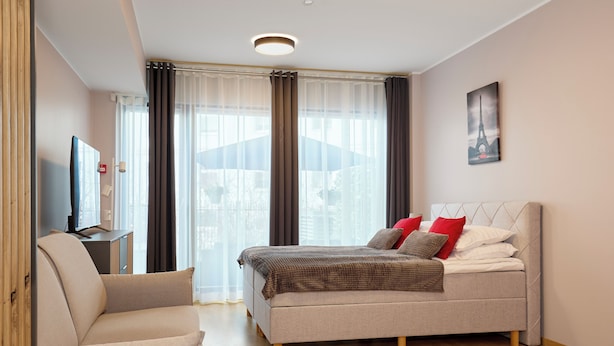 Une chambre moderne avec un lit, un canapé, un téléviseur à écran plat et un tableau représentant la Tour Eiffel.