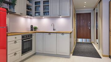 A compact kitchen with a built-in oven, a sink, and a red refrigerator.