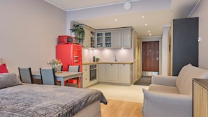 Un espace de vie compact comprenant une kitchenette, un coin repas et une chambre.