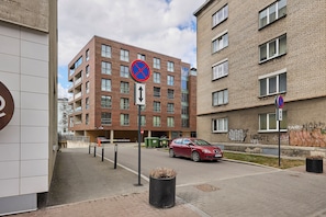 Ein mehrgeschossiges Wohngebäude mit Parkhausauffahrt, einem Verbotsschild und einem roten Auto vor der Fassade.