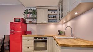 Une cuisine de taille réduite avec un réfrigérateur rouge, un four encastré et un plan de travail en bois.
