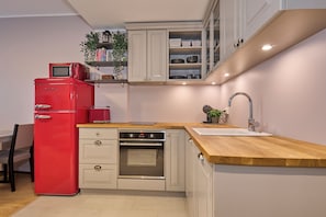 Eine kleine Küche mit einem roten Kühlschrank, einem eingebauten Backofen und einer Holz Arbeitsplatte.