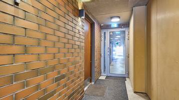A hallway with a brick wall, a door with a glass panel, and a carpeted entrance.