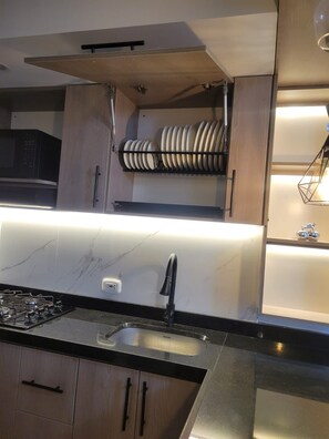 A modern kitchen with a built-in stove, a sink, and a microwave.