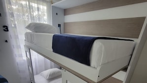 Una cama litera con cabecera blanca, manta azul y colchón blanco.