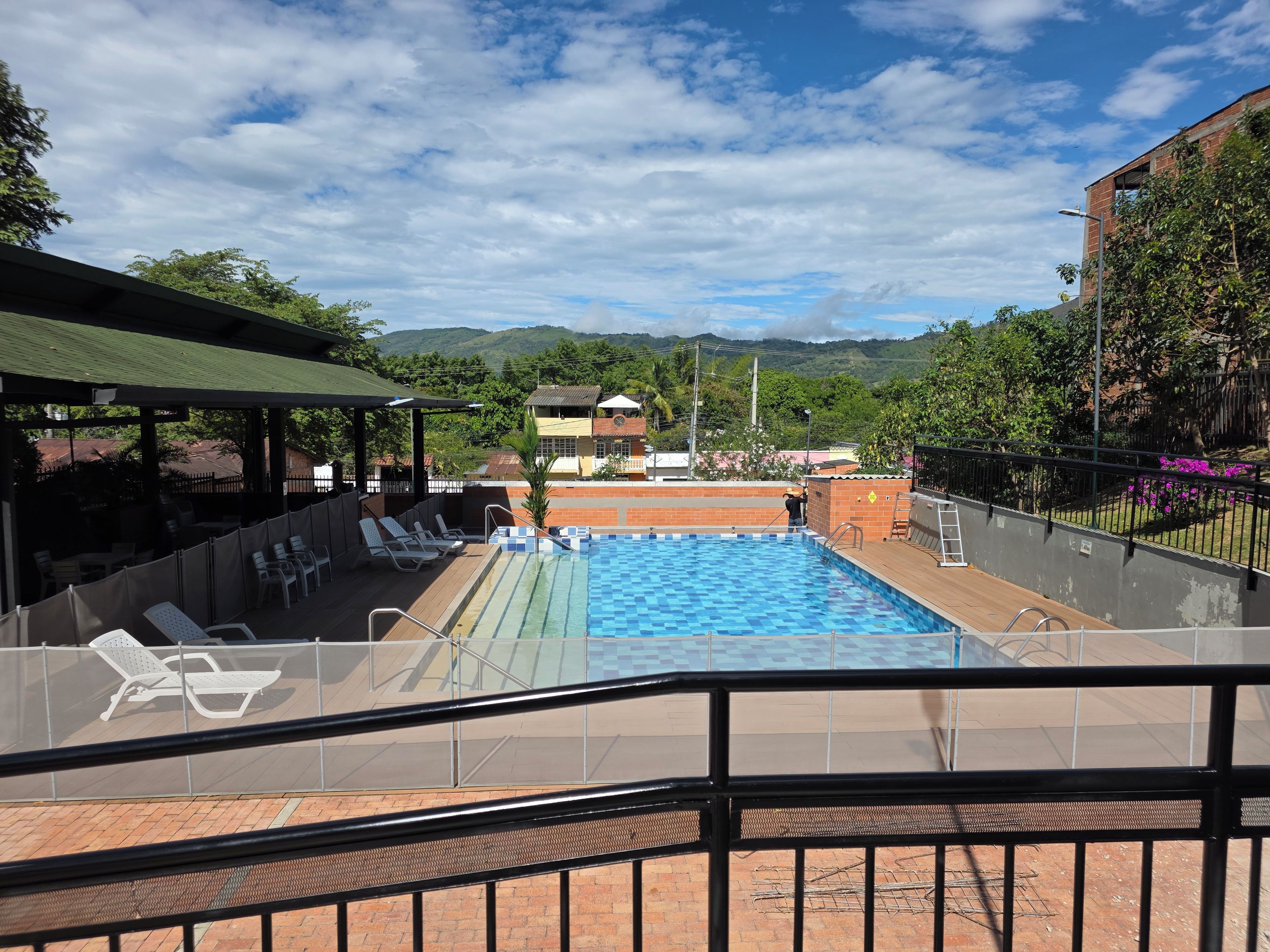 Una piscina con vistas a montañas, un área de descanso techada y una terraza amurallada.