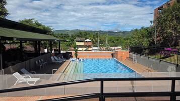 Una piscina con vistas a montañas, un área de descanso techada y una terraza amurallada.
