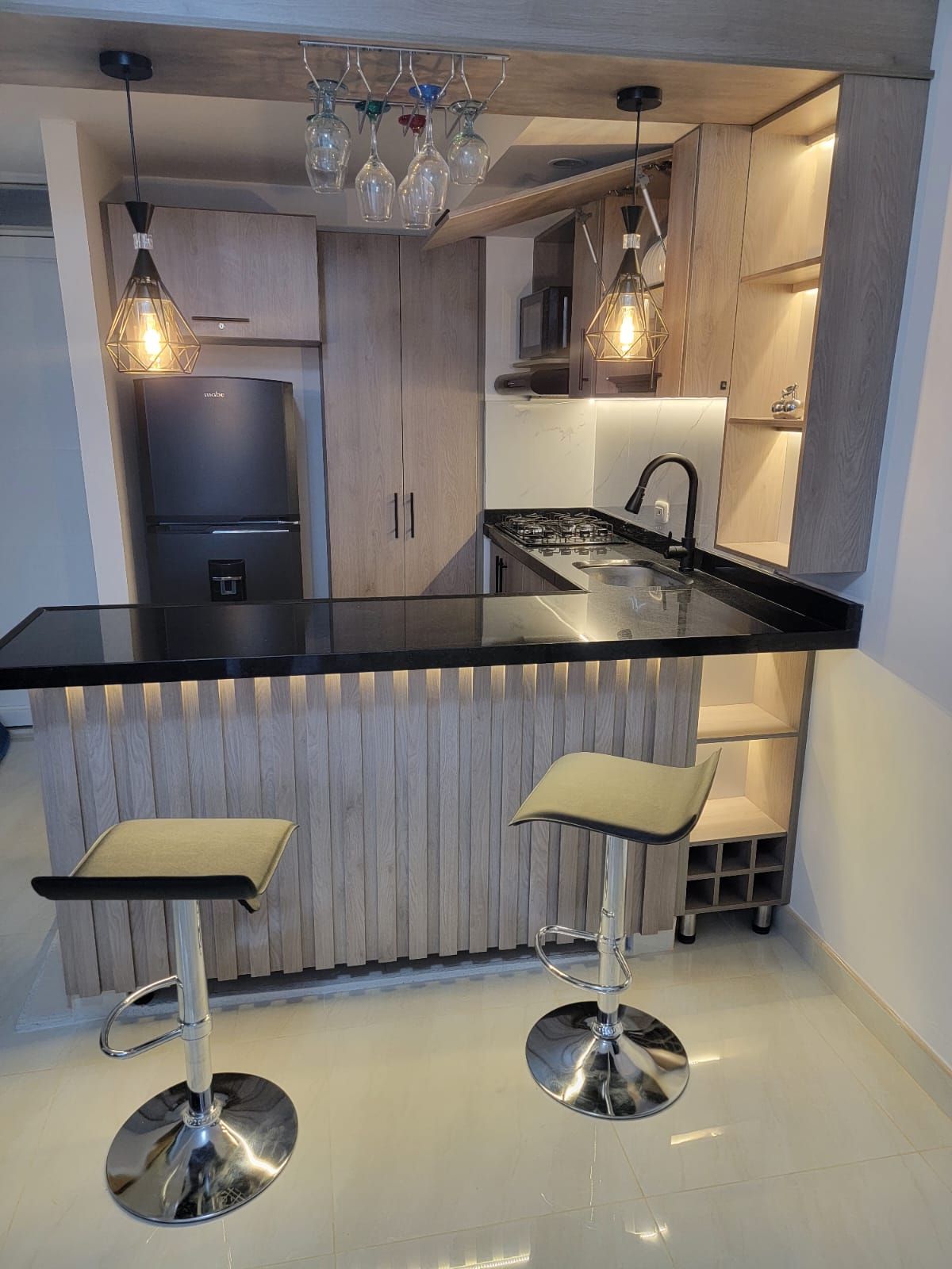 Una cocina moderna con encimera negra, electrodomésticos de acero inoxidable y armarios de madera.