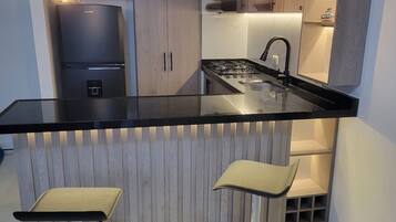 Una cocina moderna con encimera negra, electrodomésticos de acero inoxidable y armarios de madera.