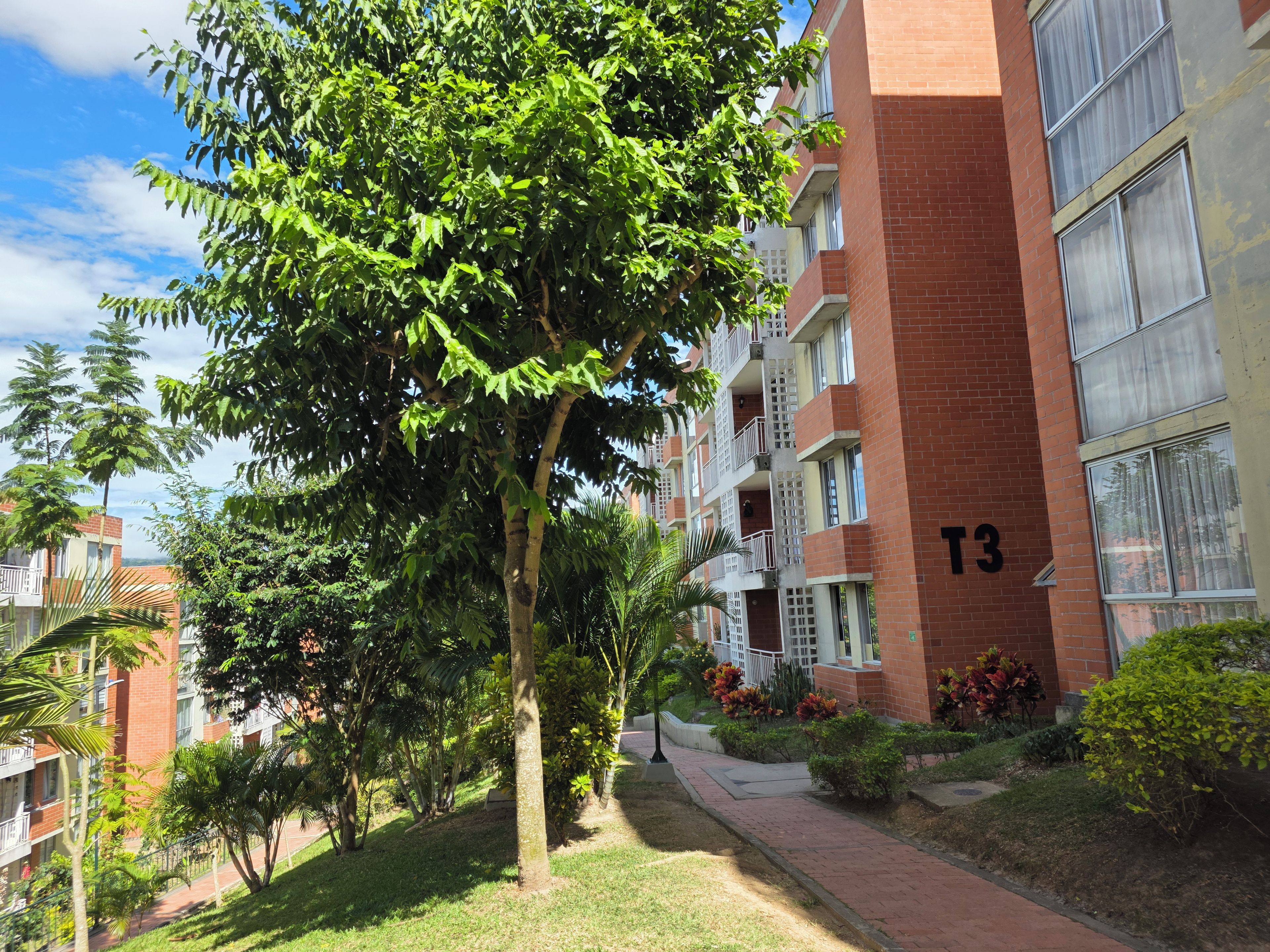 Un edificio residencial de varios pisos con balcones, fachada de ladrillo y un cartel con el número 'T3'.
