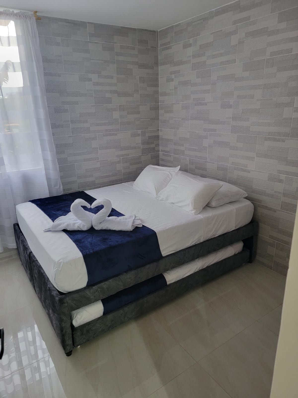 Un dormitorio moderno con una cama, un cojín azul decorativo y un cojín con forma de cisne.