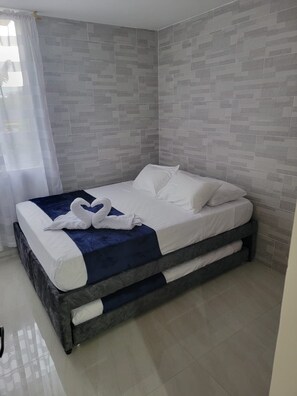 A modern bedroom with a bed, a blue accent pillow, and a decorative swan pillow.