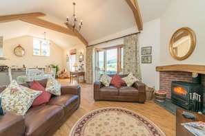 A cozy living room with leather sofas, a fireplace, and a dining area with natural light.