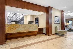 A reception area with a marble counter, wooden paneling, a framed picture on the wall, and a patterned chair. - Spacious Studio w/ Kitchen | Pool + Hot Breakfast (Warrendale)
