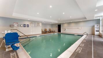Ein Hallenbad mit Rettungsschwimmerstuhl, Liegestühlen und Sicherheitsschildern.