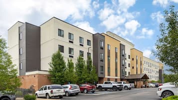 A multi-story hotel with a parking lot, a covered entrance, and a brick facade.