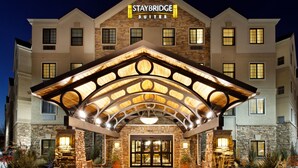 Een Staybridge Suites hotel met een stenen gevel, een ruime entree en een overdekt terras.