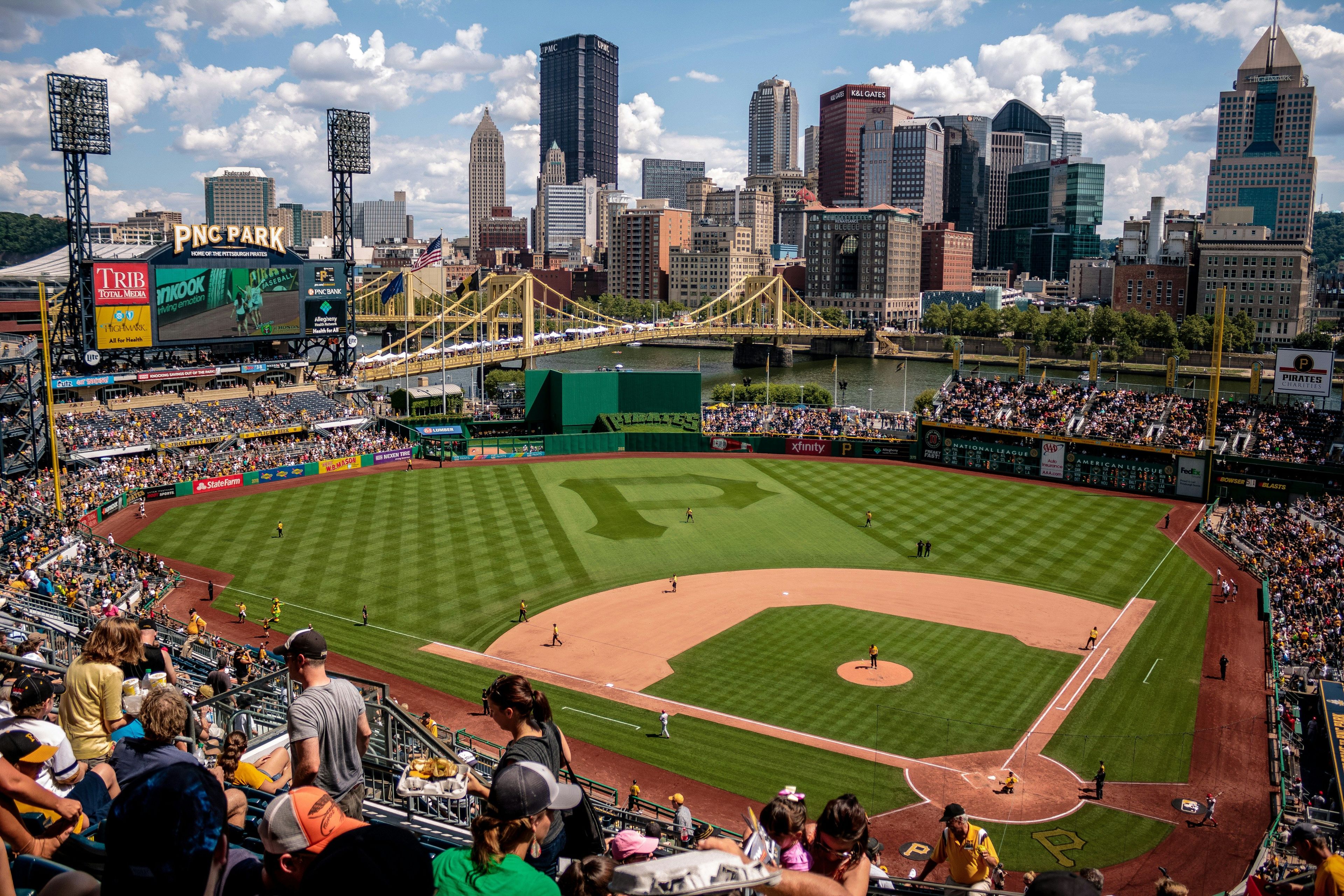 Ein Baseballstadion mit einer großen Anzeigetafel, einer Skyline im Hintergrund und einem Fluss.