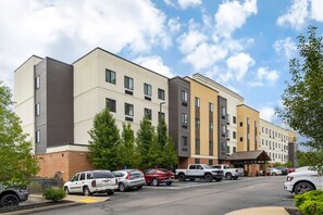 A multi-story hotel with a parking lot, a covered entrance, and a brick facade.