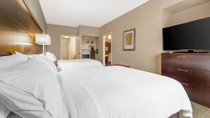 Een hotelkamer met twee bedden, een televisie, een dressoir en een badkamer zichtbaar door een geopende deur.