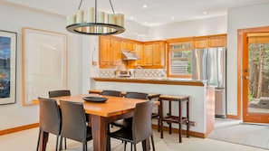 Une cuisine moderne avec des meubles en bois, un îlot central et un coin repas comprenant une table et des chaises.