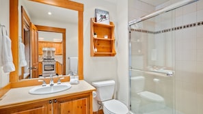 Une salle de bain avec un meuble-lavabo en bois, un évier, des toilettes et une douche à parois de verre.