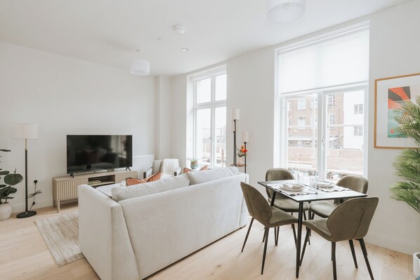 Una sala de estar moderna con sofá, televisor, mesa de comedor y sillas.