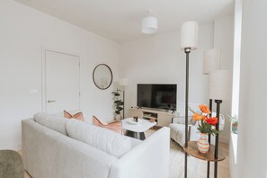A modern living room with a sofa, coffee table, TV, and decorative lamps. - Premium London Stay – Luxury 1-Bed Apartment (London)