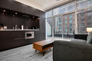 Eine moderne Küche mit dunklen Schränken, einem eingebauten Ofen und einem Fenster mit Blick auf die Skyline.