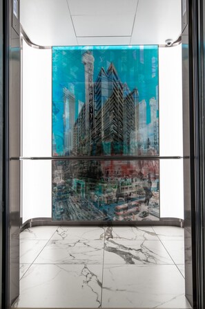 Ein Aufzug mit Glaswand, der einen Blick auf eine Skyline mit hohen Gebäuden bietet.
