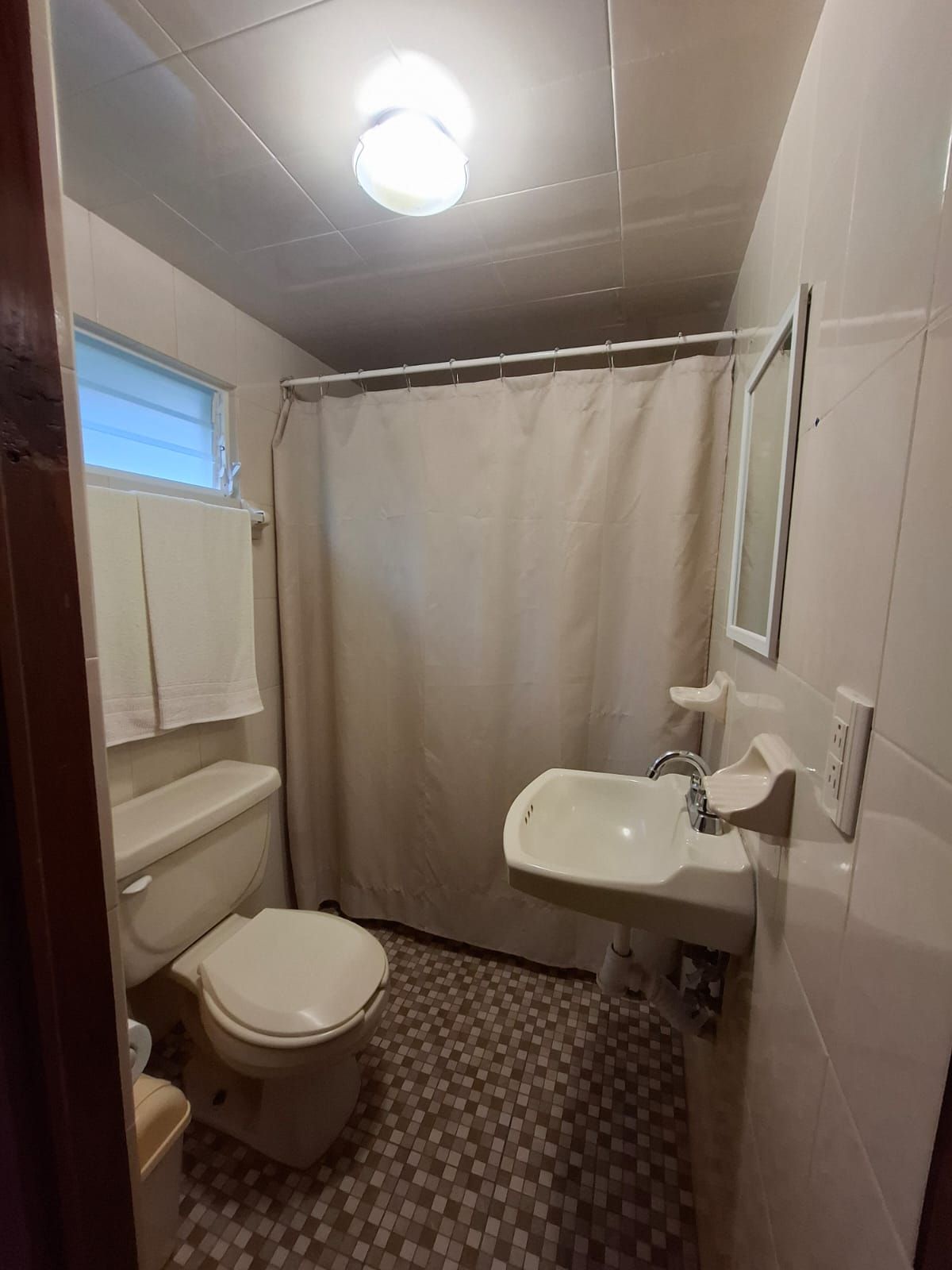 A bathroom with a toilet, sink, and shower curtain.