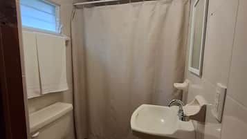 Et badeværelse med toilet, vask og badeforhæng.