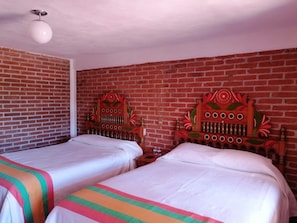 A room with two beds, each with a wooden headboard, a brick wall, and a round ceiling light. - 7 ROBLES (Tlalpujahua)