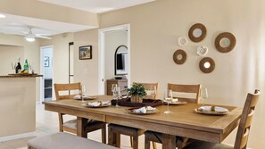 A dining area with a wooden table set for four, surrounded by chairs. - Coralvine by Avantstay Screened Heated Pool + Lanai & Grill Near Beach + Mercato (Naples)