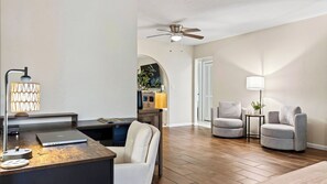 A modern living room with a desk, two armchairs, a ceiling fan, and a lamp. - Coralvine by Avantstay Screened Heated Pool + Lanai & Grill Near Beach + Mercato (Naples)