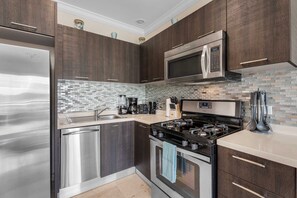 A modern kitchen with stainless steel appliances, dark wood cabinets, and a tiled backsplash. - PC404 - Pool View - 1 BR Perfect  for a couple - Close to Palm Beach - 1BR (Palm Beach)