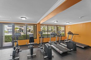 Ein Fitnessraum mit Cardiogeräten und Spiegeln, großen Fenstern und Blick ins Freie.
