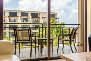 A balcony with two chairs and a small table, overlooking a building with multiple windows and balconies. - PC404 - Pool View - 1 BR Perfect  for a couple - Close to Palm Beach - 1BR (Palm Beach)